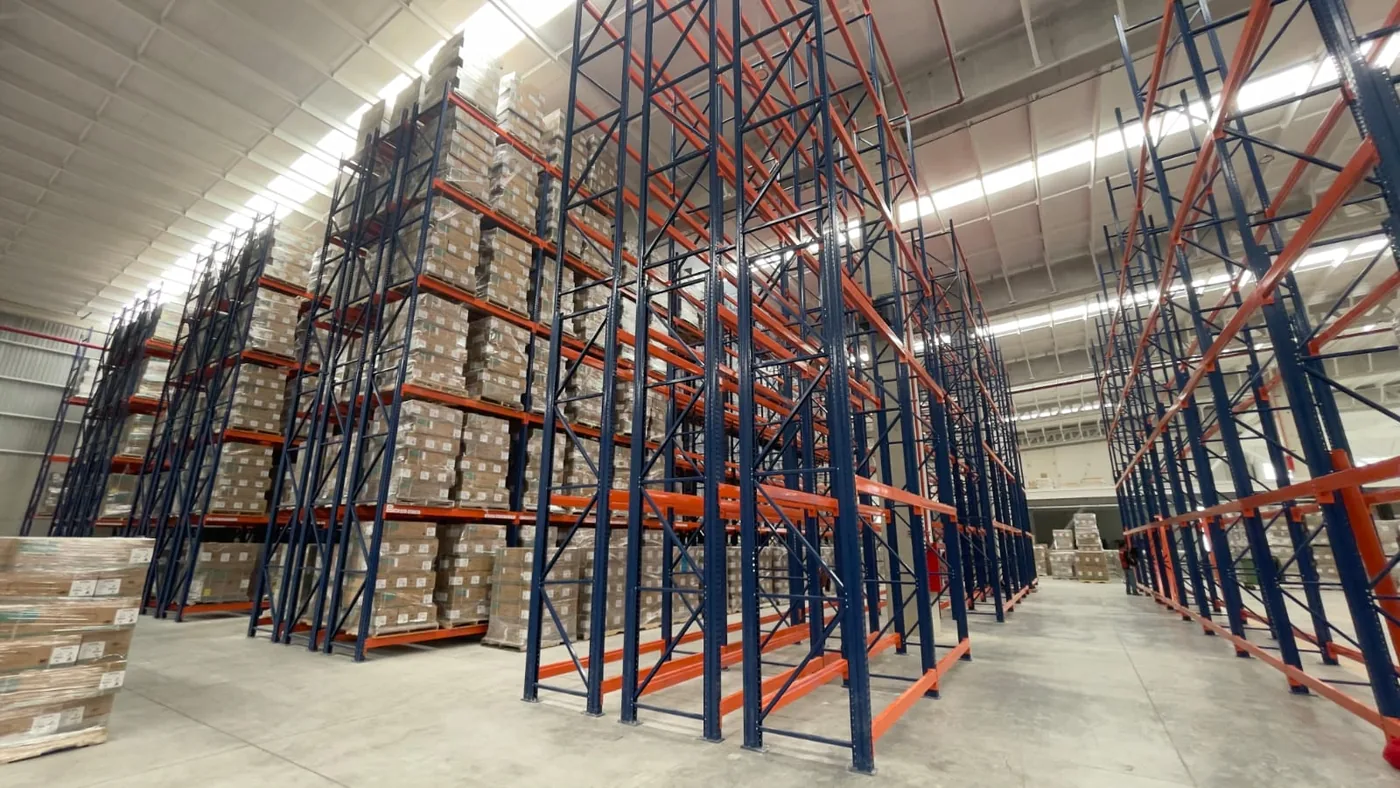 Racks industriales azules y naranjas de gran altura en nave