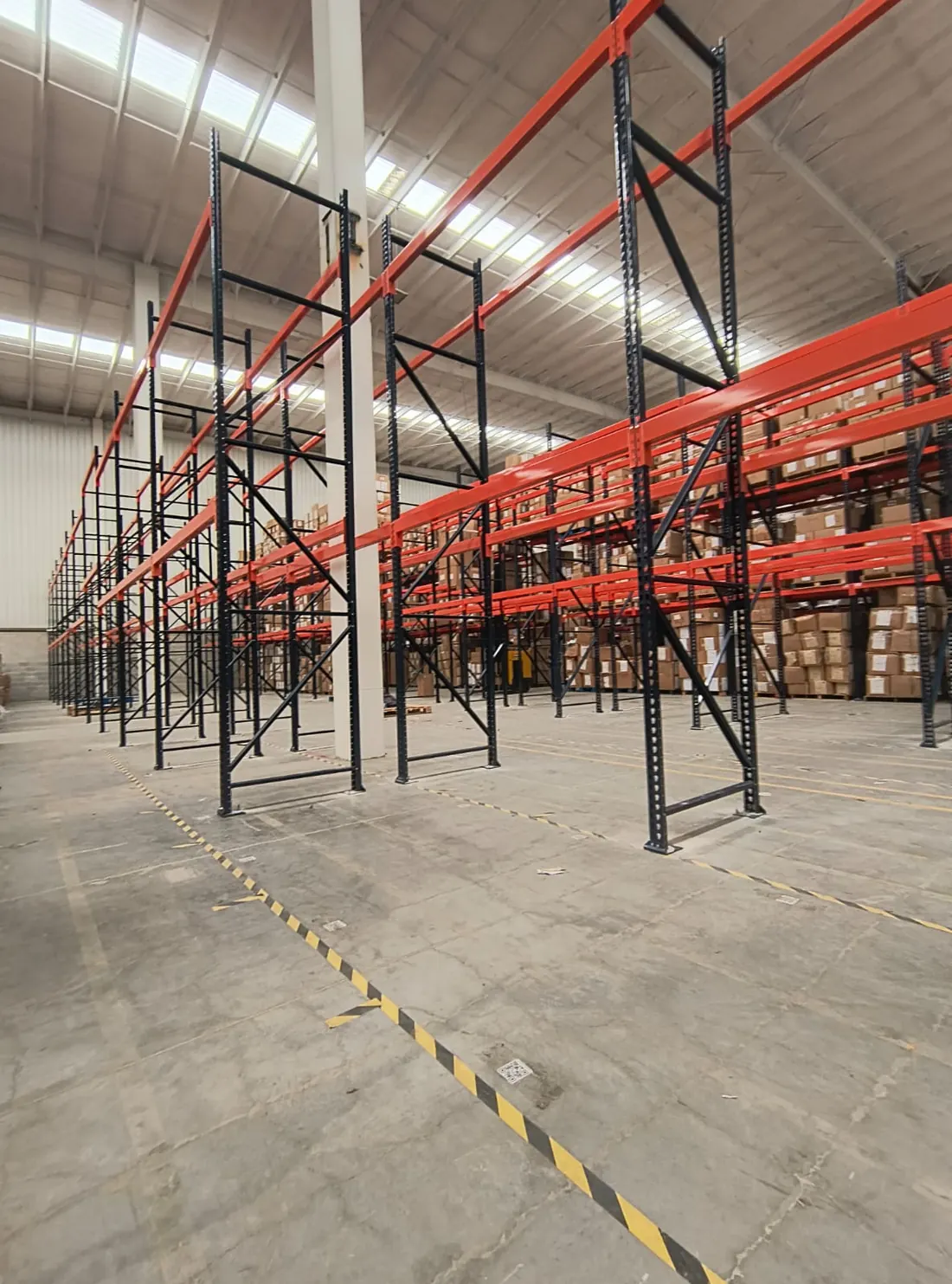 Racks industriales rojos y negros cargados de cajas en almacén
